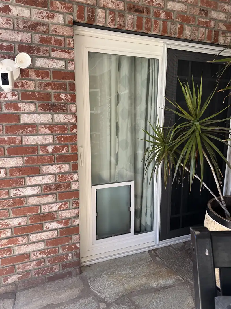 Pet door installed in the glass of a white sliding patio door